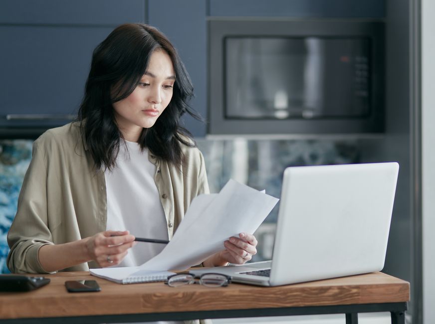 노트북 화면을 보며 서류를 확인하는 사람
